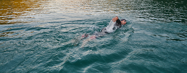 Image showing A professional triathlete trains with unwavering dedication for an upcoming competition at a lake, emanating a sense of athleticism and profound commitment to excellence.