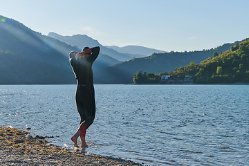 Image showing Authentic triathlon athlete getting ready for swimming training on lake