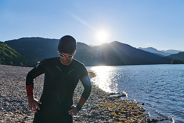 Image showing Authentic triathlon athlete getting ready for swimming training on lake