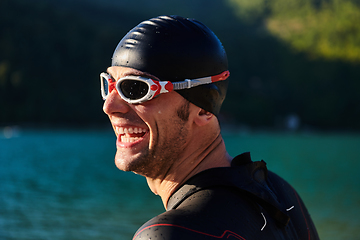 Image showing Authentic triathlon athlete getting ready for swimming training on lake