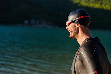 Image showing Authentic triathlon athlete getting ready for swimming training on lake