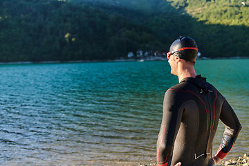 Image showing Authentic triathlon athlete getting ready for swimming training on lake