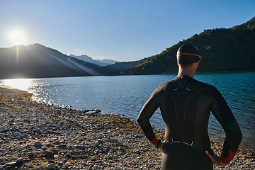 Image showing Authentic triathlon athlete getting ready for swimming training on lake