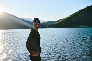 Image showing Authentic triathlon athlete getting ready for swimming training on lake