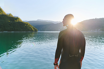 Image showing Authentic triathlon athlete getting ready for swimming training on lake