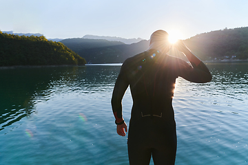 Image showing Authentic triathlon athlete getting ready for swimming training on lake