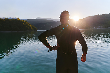 Image showing Authentic triathlon athlete getting ready for swimming training on lake