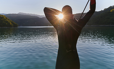 Image showing Authentic triathlon athlete getting ready for swimming training on lake