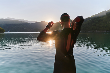 Image showing Authentic triathlon athlete getting ready for swimming training on lake