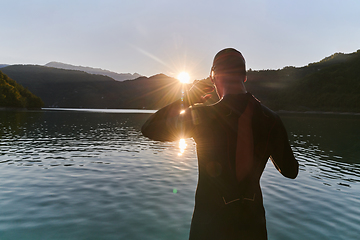 Image showing Authentic triathlon athlete getting ready for swimming training on lake