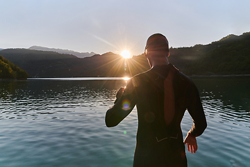 Image showing Authentic triathlon athlete getting ready for swimming training on lake