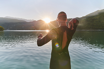 Image showing Authentic triathlon athlete getting ready for swimming training on lake