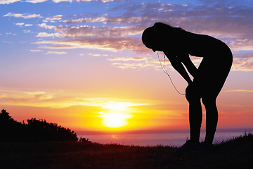 Image showing Sunset, exercise silhouette and sea with tired person after running and travel outdoor with freedom. Vacation, holiday and ocean in the morning by the beach and fatigue with workout and break by sun