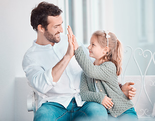 Image showing Father, girl child and happy with high five, smile and hug with care, love and bonding on chair in home. Dad, kid and cheers with success, support and motivation at family house for celebration