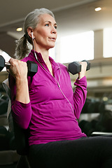 Image showing Senior fitness, old woman and dumbbell at gym for training, wellness or cardio with earphones, music or mindset. Weightlifting, bodybuilding and elderly female person at sports center for arm workout