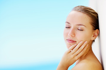 Image showing Woman, wall and outdoor with skincare, beauty and hands of face for results by blue sky background. Girl, touch skin and facial change with cosmetics, wellness or transformation with space in nature