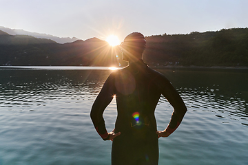 Image showing Authentic triathlon athlete getting ready for swimming training on lake