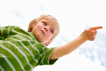 Image showing Children, sky background and a serious boy pointing to blame from below while outdoor on a summer day. Kids, warning and hand gesture with a confident young child in a natural or cloudy environment