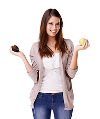 Image showing Portrait, decision and apple or muffin with a woman in studio isolated on a white background for food choice. Smile, diet or nutrition with a happy young person holding fruit and dessert options