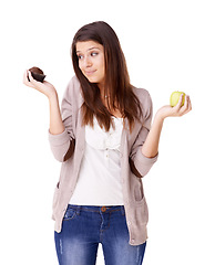 Image showing Confused, decision and apple or muffin with a woman in studio isolated on a white background for food choice. Doubt, diet or nutrition with an unsure young person holding fruit and dessert options