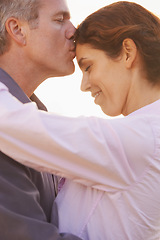 Image showing Couple, forehead kiss and hug with love, respect or happiness on holiday in retirement. Mature, man and woman embrace together outdoor at sunset on vacation or show affection or gratitude in marriage