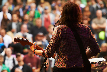 Image showing Musician, music festival and stage in outdoors, guitarist and event or energy for freedom at party. Person, back and concert or rave, audio and song for fun crowd and entertainment for audience