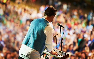 Image showing Musician, music festival and stage in outdoors, keyboard and event or energy for freedom at party. Person, back and concert or rave, audio and piano for fun crowd and entertainment for audience