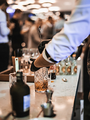 Image showing Expert barman is making cocktail at business banquet event in hotel conference center. Blurred businesspeople at banquet event business meeting event in the background