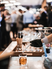 Image showing Expert barman is making cocktail at business banquet event in hotel conference center. Blurred businesspeople at banquet event business meeting event in the background