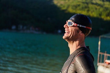 Image showing Authentic triathlon athlete getting ready for swimming training on lake