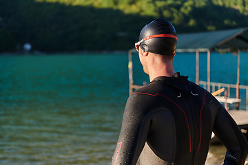 Image showing Authentic triathlon athlete getting ready for swimming training on lake