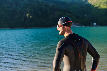 Image showing Authentic triathlon athlete getting ready for swimming training on lake