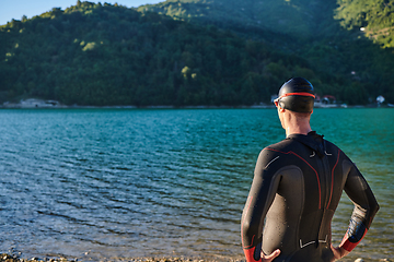 Image showing Authentic triathlon athlete getting ready for swimming training on lake