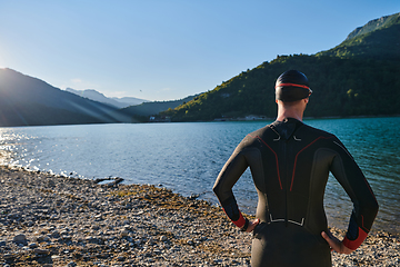 Image showing Authentic triathlon athlete getting ready for swimming training on lake