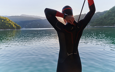 Image showing Authentic triathlon athlete getting ready for swimming training on lake