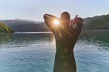 Image showing Authentic triathlon athlete getting ready for swimming training on lake