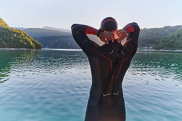 Image showing Authentic triathlon athlete getting ready for swimming training on lake