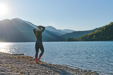 Image showing Authentic triathlon athlete getting ready for swimming training on lake