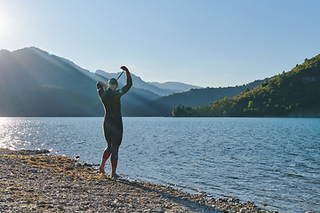 Image showing Authentic triathlon athlete getting ready for swimming training on lake