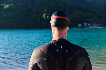 Image showing Authentic triathlon athlete getting ready for swimming training on lake