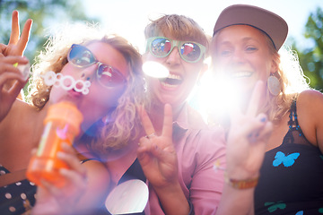 Image showing Portrait, peace sign and happy friends in sunglasses outdoor, blowing bubbles and funny laugh together in summer. Face, women and group of girls with v hand gesture, excited and lens flare in nature