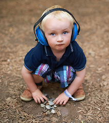 Image showing Protection, boy and outdoor with headphones, portrait and relax with nature, playing and summer. Toddler, kid and childhood with noise cancelling headset, outside and sound in a park and safety