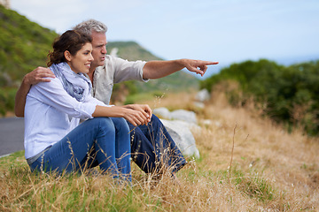 Image showing Mature, couple and pointing at nature on holiday, vacation or embrace with love or support in retirement. Happy, man and woman together sightseeing on hill, mountain or relax in environment adventure