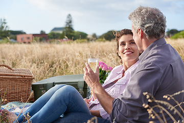 Image showing Mature, couple relax and picnic in park on date with love, care or support in marriage. Outdoor, man and woman on grass in nature with drink, flowers or celebration in summer, holiday or vacation