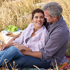 Image showing Mature couple, date and picnic in park to relax with love, care or support in marriage. Outdoor, man and embrace woman on grass in nature with food, drinks or celebration together on vacation