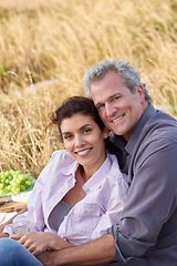 Image showing Mature couple, portrait and picnic in park for a date with love, care or support in marriage. Happy, man and woman relax on grass with food, nature and hug in celebration on holiday or vacation