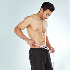 Image showing Stomach, measuring tape and fitness man in studio with Weight loss, progress or bmi control on white background. Body, wellness and male model with waist measurement for diet, health or sixpack check