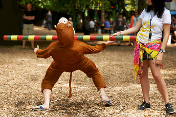Image showing Summer, vacation and man in game of limbo, balance and playing at a music festival, event and challenge. Fun, people and outdoor in woods, forest or person in social activity at party in monkey suit