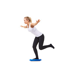 Image showing Balance, health and workout with woman on disk in studio for fitness, body or exercise. Wellness, challenge and training with female person on white background for flexibility, smile or aerobics