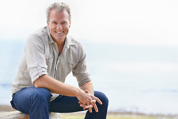 Image showing Happy, mature man and portrait on holiday at beach with freedom to relax in nature with view of ocean. Smile, outdoor and person in morning on island vacation with blue sky, sea and mockup space